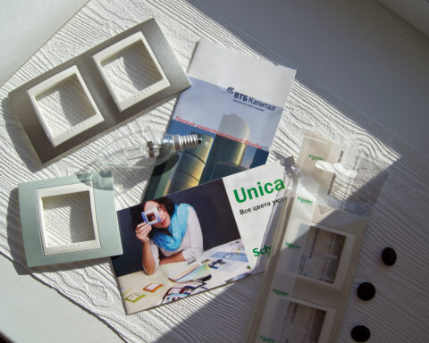 Auf einem weißen Tisch liegen Broschüren und Produktmuster von Schneider Electric und PTC in Sonnenlicht.