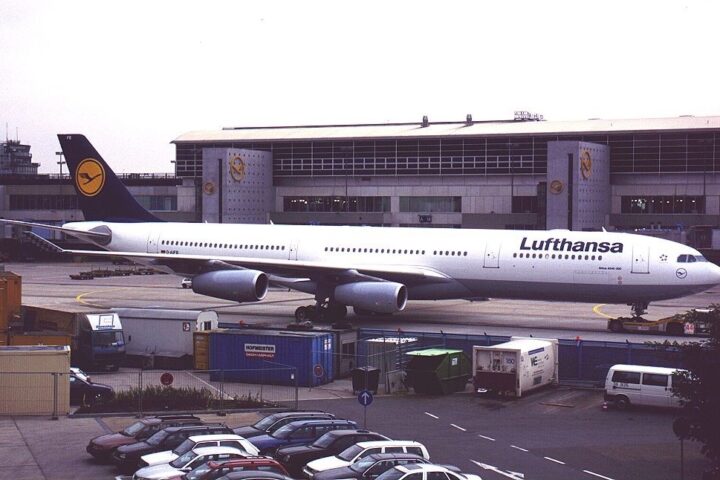 Lufthansa-Flugzeug auf dem Vorfeld vor einem Flughafengebäude.