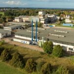 Luftaufnahme eines Industrie- und Werksgeländes mit mehreren Fabrikgebäuden im Grünen.