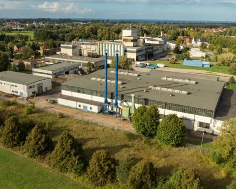 Luftaufnahme eines Industrie- und Werksgeländes mit mehreren Fabrikgebäuden im Grünen.