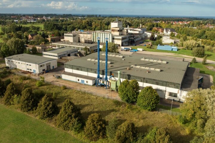 Luftaufnahme eines Industrie- und Werksgeländes mit mehreren Fabrikgebäuden im Grünen.