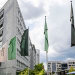 Gebäude von Boehringer Ingelheim mit mehreren Firmenfahnen vor bewölktem Himmel.