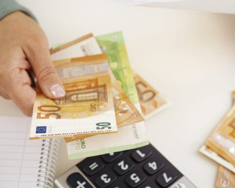 Hand zählt Euro-Banknoten neben Taschenrechner und Notizblock.