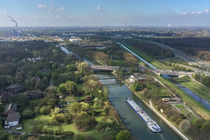 Luftaufnahme eines Industrie- und Wohngebiets mit Kanal, Straßen und Fabrikanlagen im Ruhrgebiet.