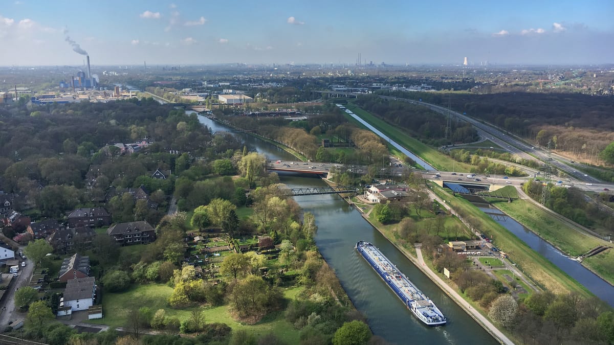 Luftaufnahme eines Industrie- und Wohngebiets mit Kanal, Straßen und Fabrikanlagen im Ruhrgebiet.