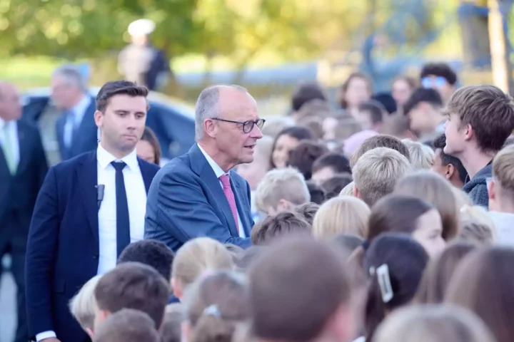 Friedrich Merz spricht bei einem Besuch im Freien mit einer Gruppe von Schülern und Begleitern.