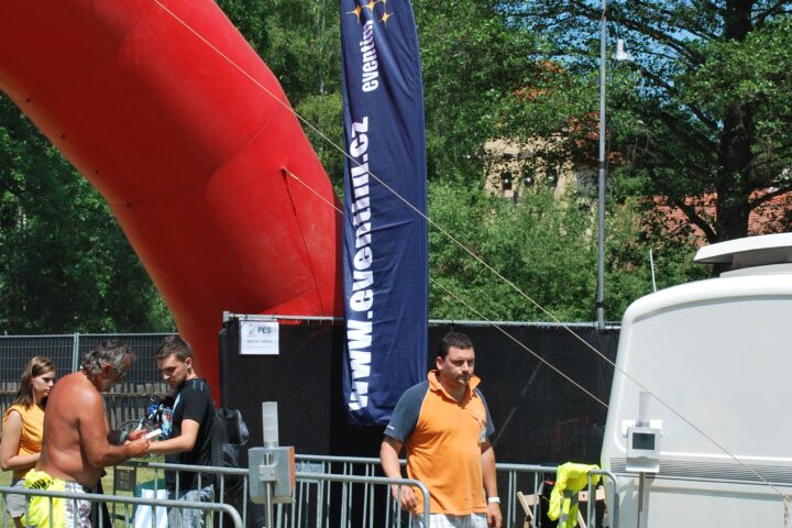 Besucher stehen an einem abgesperrten Bereich neben einem Eventim-Banner und einem großen roten Luftobjekt im Freien.