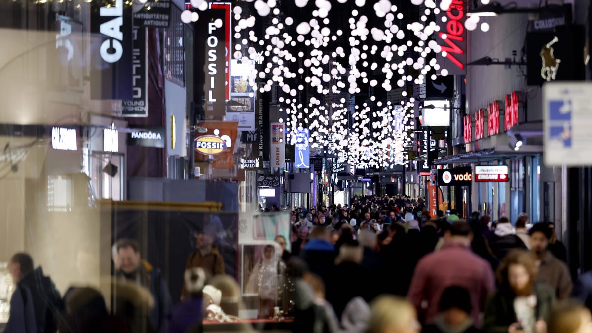 HDE meldet sinkendes Konsumbarometer und trübere Erwartungen für Weihnachten 1 Menschenmengen in einer beleuchteten Einkaufsstraße mit zahlreichen Ladenschildern.