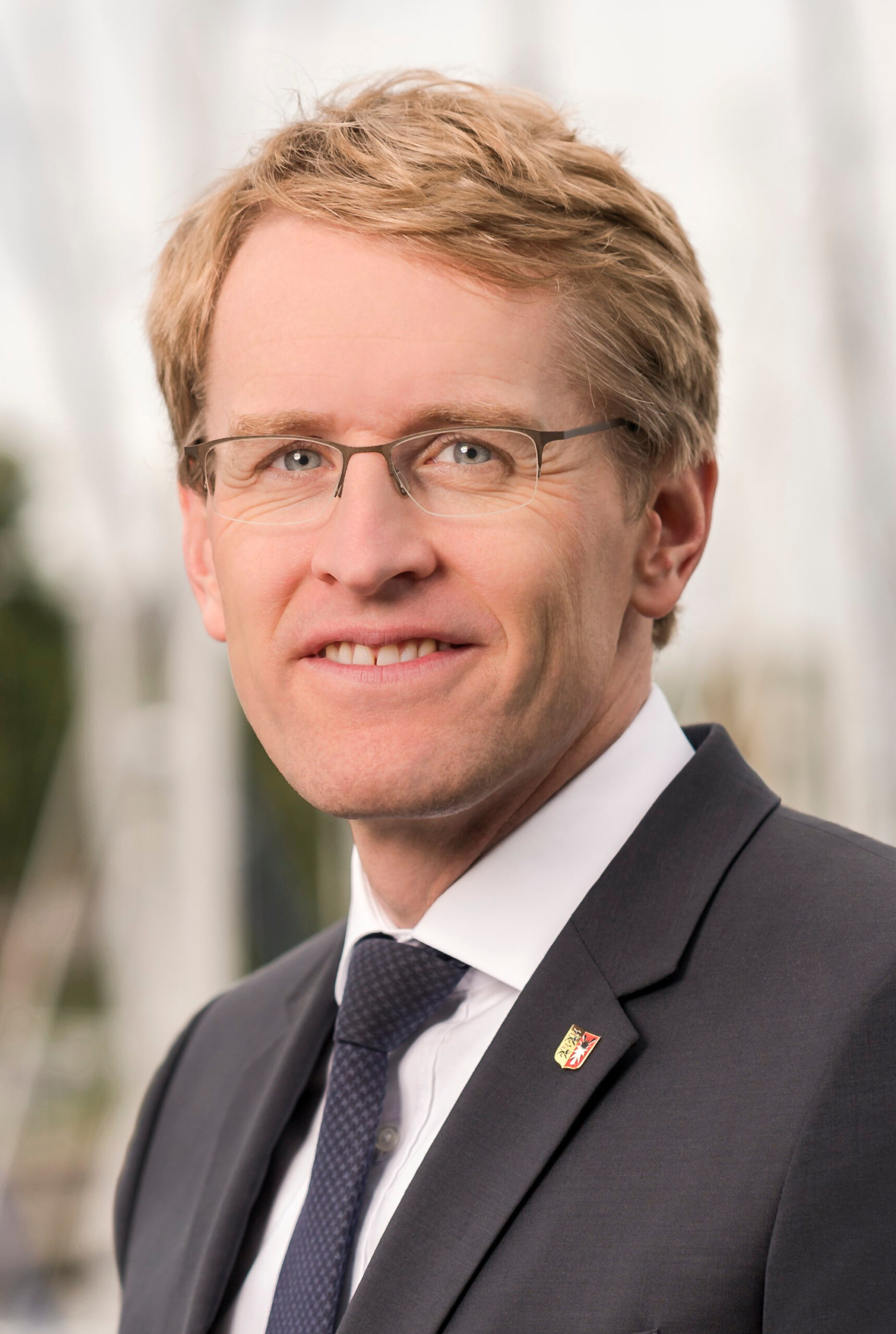 Porträt von Schleswig-Holsteins Ministerpräsident Daniel Günther im dunklen Anzug und mit Brille.